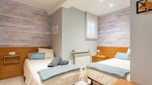 A double room with two beds, a wooden headboard, a bedside table, a nightstand, a radiator, and a starfish decoration. - Sunset Apartment on the Paseo de Mar in Front of the Beach with Wi-Fi (Sant Antoni de Calonge)
