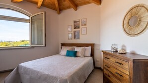 A bedroom with a bed, wooden headboard, a dresser, a mirror, and framed pictures on the wall.