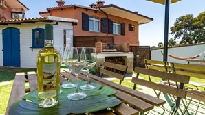 A patio with a table set for a meal, a bottle of wine, and glasses.