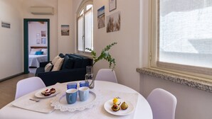 A dining area with a table set for two, a window with a view, and a door leading to another room.