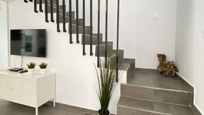 Ein modernes Interieur mit Treppe, Flachbildfernseher, weißem Sideboard und einem Blumentopf.