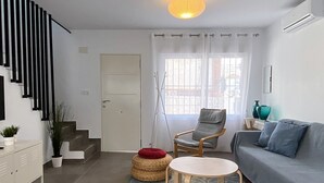 Ein modernes Wohnzimmer mit einer Couch, einem Sessel, einem kleinen Tisch, einer Treppe und einer Tür.