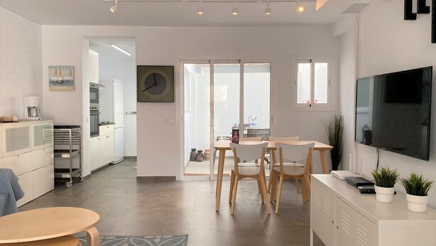 Eine moderne Küche mit Essbereich, einem an der Wand montierten Fernseher und einem großen Fenster.