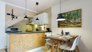 Una cocina con isla de madera, armarios blancos, microondas y un comedor con mesa y sillas.