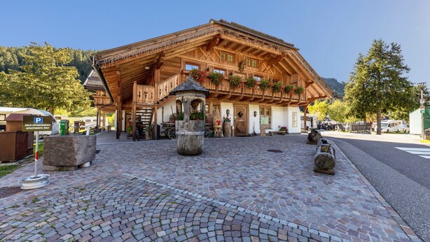 Ein traditionelles Holzgebäude mit einem Balkon, einer Steinfountain und einem Kopfsteinpflasterhof.