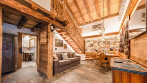 Un intérieur rustique avec un mur en pierre, un escalier en bois et un canapé.