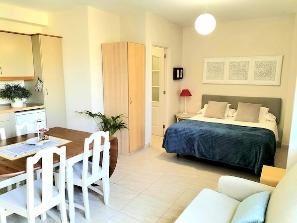 A bedroom with a bed, bedside table, lamp, and wall art.
