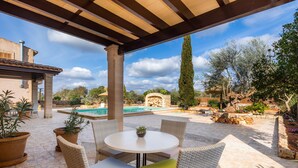 An outdoor patio with wicker furniture, a pool, and a stone wall.