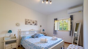 Une chambre à coucher avec un lit, des tables de chevet, un miroir et une fenêtre avec des rideaux.