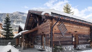 Une cabane rustique en bois, avec des fondations en pierre, un porche en bois et un toit recouvert de neige.