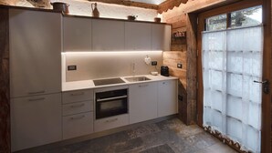 Une cuisine moderne dotée d’un four encastré, d’un évier et de poutres en bois au plafond.