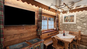 Un intérieur en bois avec une télévision, une table et des chaises, ainsi qu’un banc.
