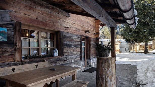 Un bâtiment rustique en bois, avec un banc et une table à l’extérieur.