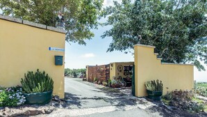 A gated entrance with a sign, potted plants, and a bicycle. - Pet-Friendly Apartment B Armonia Rural with Sea View, Terrace, Shared Pool & Wi-Fi (Granadilla de Abona)