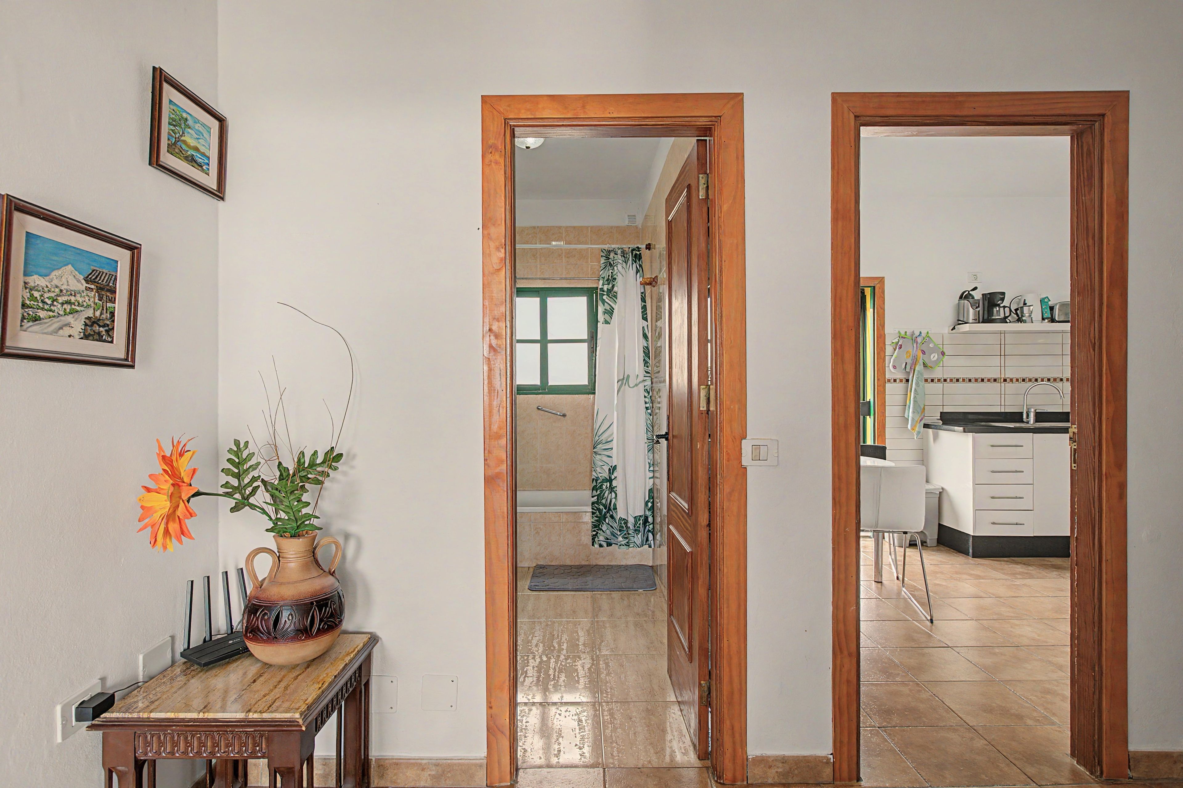 Un pasillo que conduce a un baño con cortina de ducha y una cocina con armarios y un lavabo.