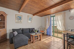 A cozy living room with a sofa, a small table, and a dining area with a chair. - Pet-Friendly Apartment B Armonia Rural with Sea View, Terrace, Shared Pool & Wi-Fi (Granadilla de Abona)