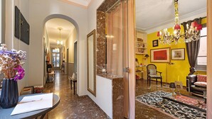 Un pasillo que conduce a una sala de estar con una araña, una alfombra estampada y un sofá.