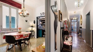 Un comedor con una mesa y sillas, una araña y una cocina visible a través de una puerta abierta.