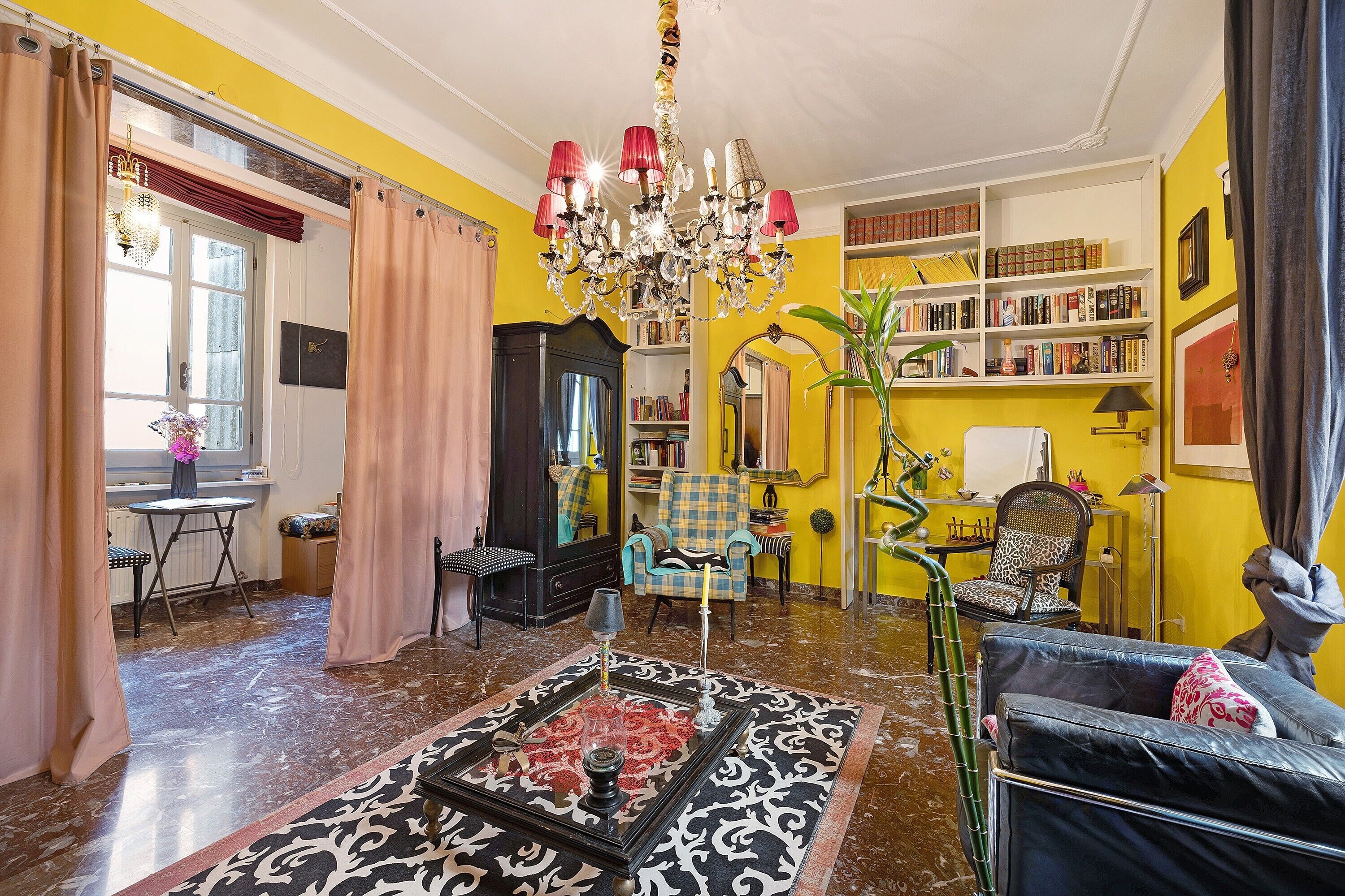 Ein Zimmer mit einer Chandelüster, Bücherregalen, einem Sofa und einem Essbereich.