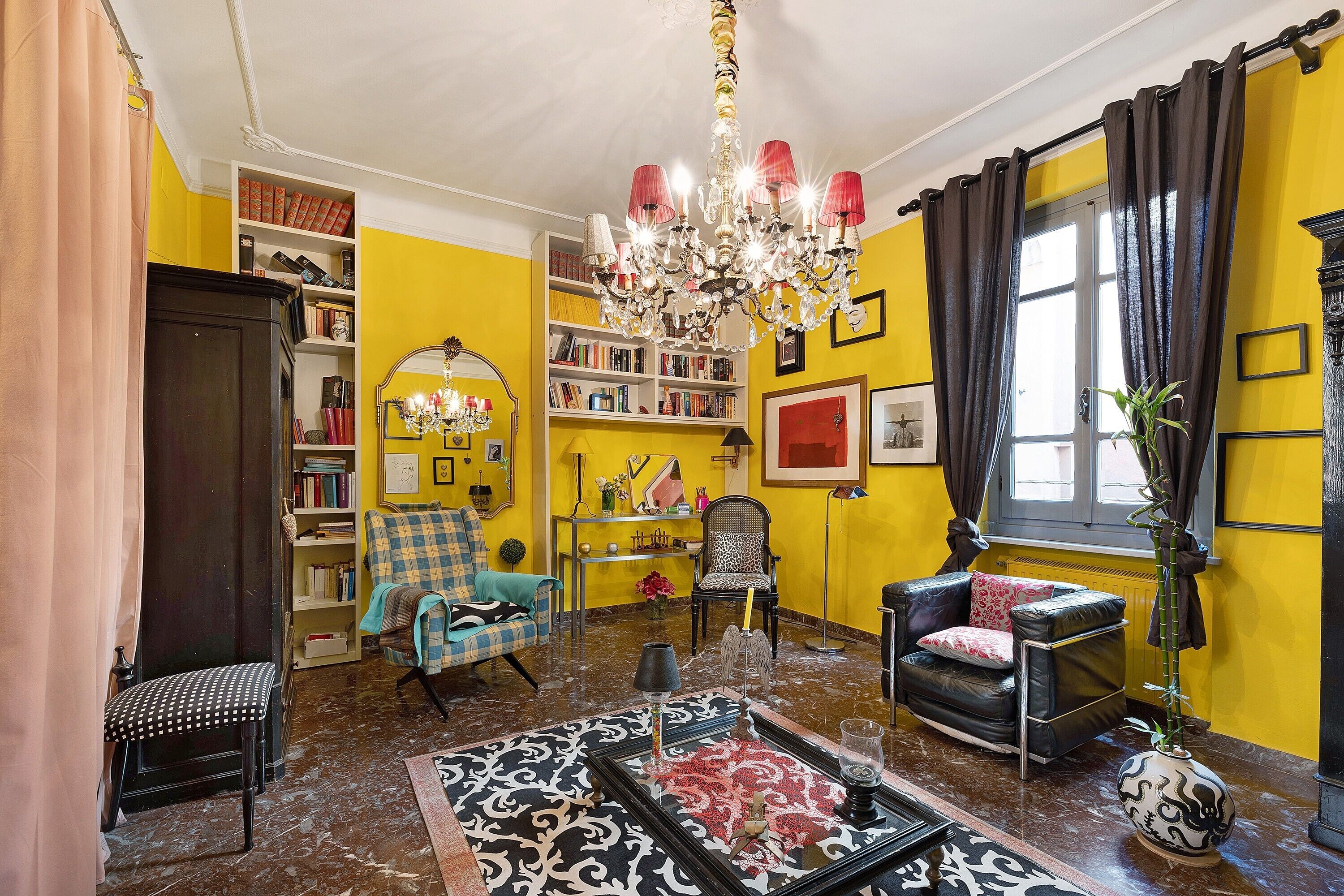 A room with a chandelier, a bookshelf, a sofa, and a coffee table.