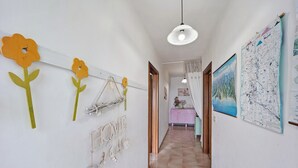 Un pasillo con pared blanca, un candelabro y un mapa.