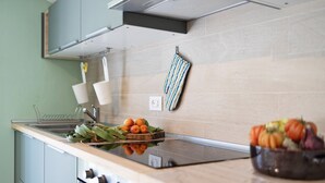 A modern kitchen with a glass cooktop, stainless steel appliances, and a wooden countertop.