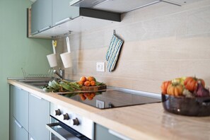 Una cocina moderna con una placa vitrocerámica, electrodomésticos de acero inoxidable y encimera de madera.