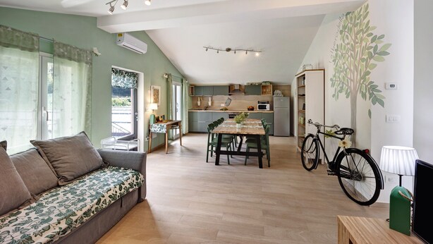 A spacious living area with a sofa, dining table, and chairs, a kitchen in the background, and a bicycle.
