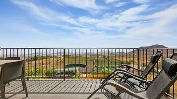 A balcony with a view of a vineyard and distant mountains.