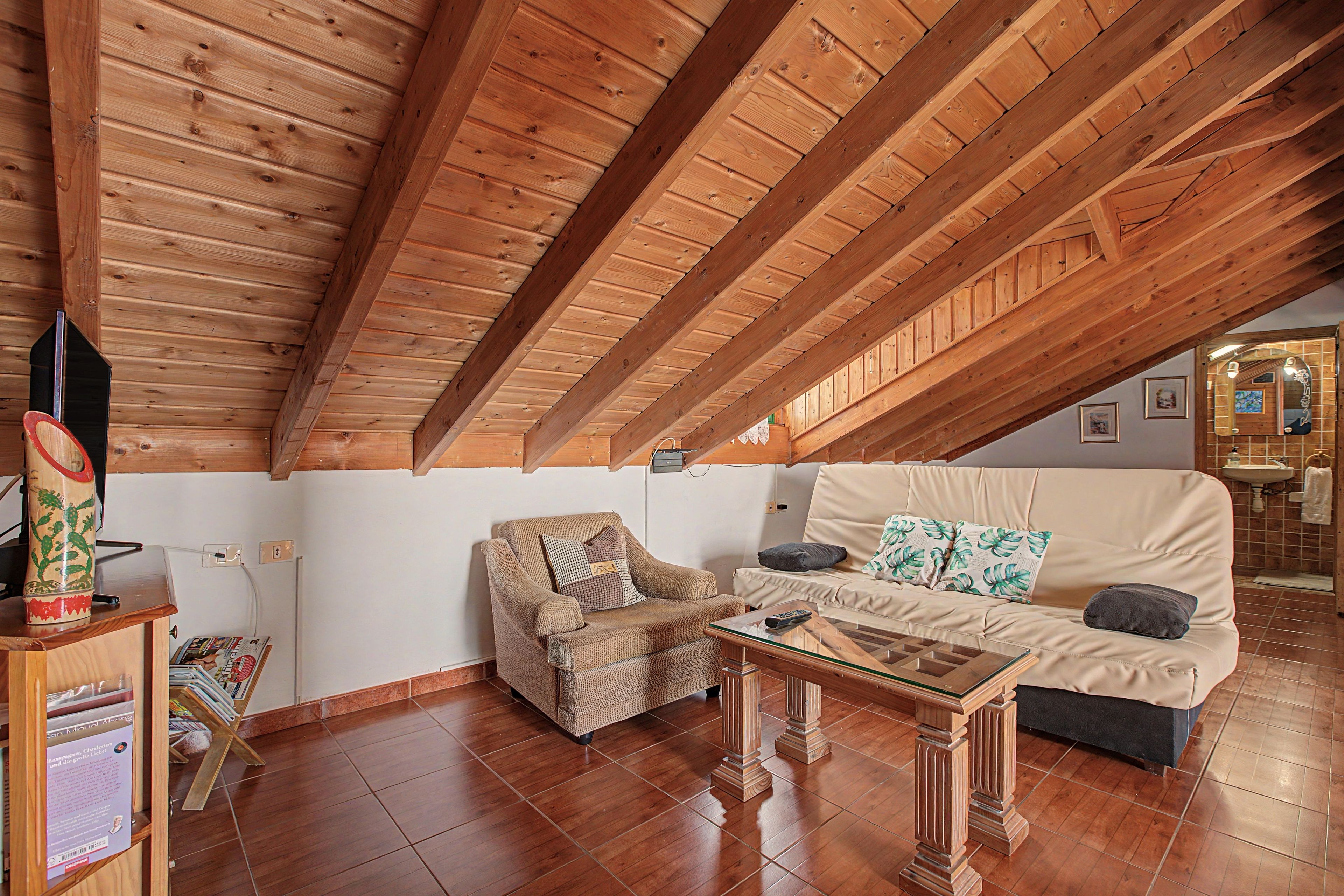 Una sala de estar acogedora con techo de madera, un sofá, un sillón y una mesita de centro.