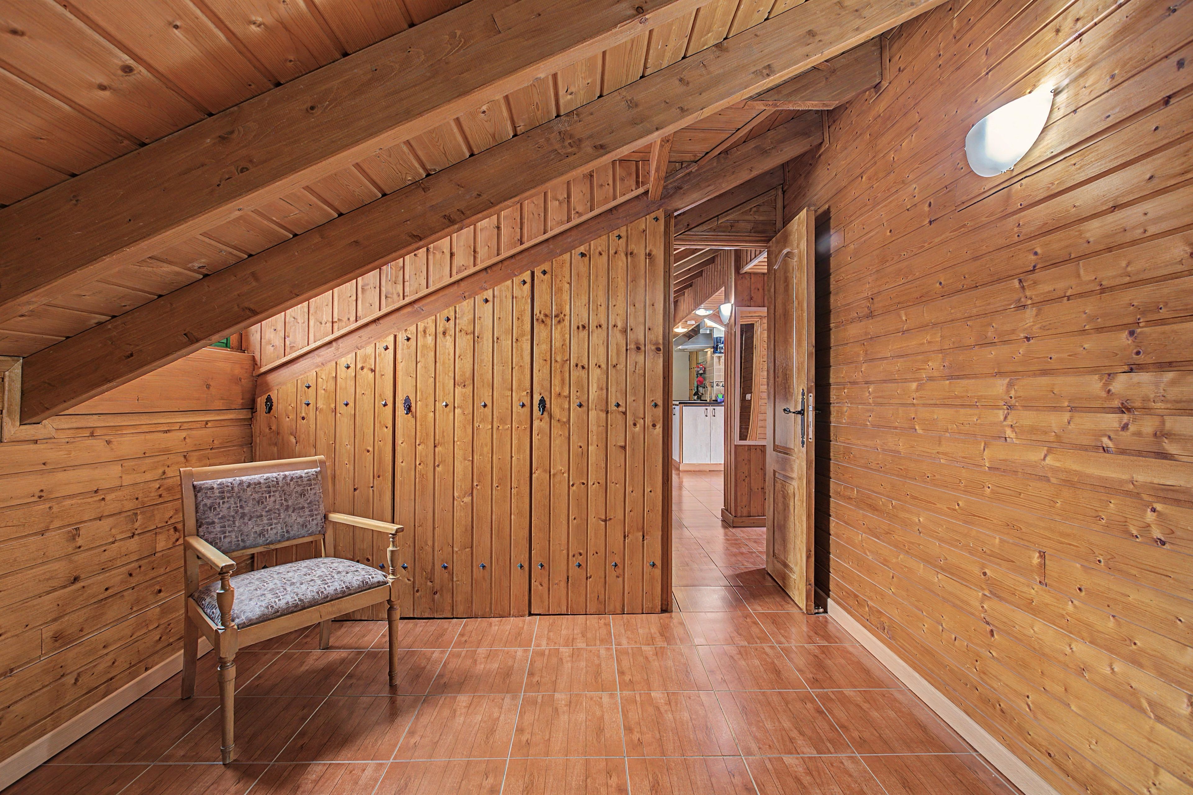 Un intérieur en bois avec un banc, un escalier et un coin cuisine à l’arrière-plan.