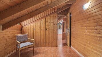 Un intérieur en bois avec un banc, un escalier et un coin cuisine à l’arrière-plan.