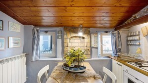 A dining area with a wooden table, chairs, a ship-shaped centerpiece, and a stone fireplace. - Apartment "Mansarda Dei Pescatori" Near Harbour (Imperia)