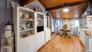 A kitchen with wooden cabinets, a dining table, and a window. - Apartment "Mansarda Dei Pescatori" Near Harbour (Imperia)