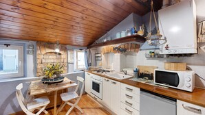 A kitchen with wooden ceiling beams, white cabinets, a microwave, and a stove. - Apartment "Mansarda Dei Pescatori" Near Harbour (Imperia)