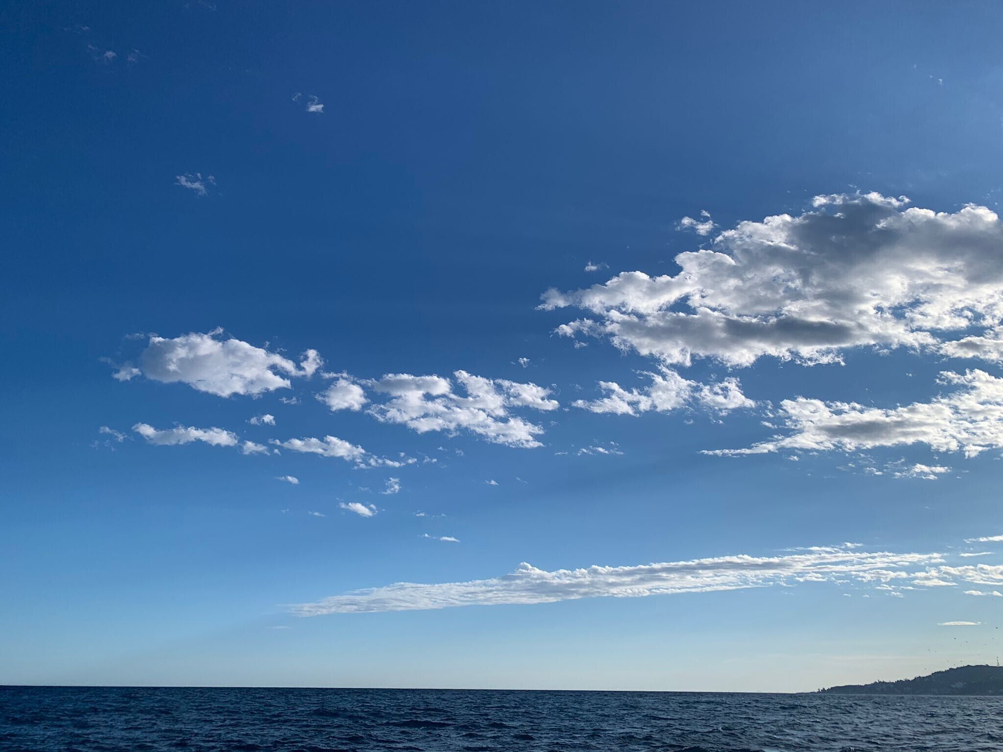 Klarer Himmel mit vereinzelten Wolken über einem Gewässer.
