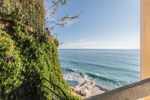 Vista costera con un acantilado rocoso, vegetación y una zona de piscina.