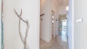 A hallway with a wooden branch decoration, white walls, and a tiled floor.