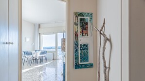 A room with a dining table, chairs, a window, and a wall-mounted artwork.