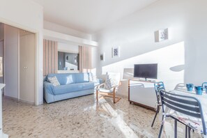 Una sala de estar moderna con un sofá, una silla, un televisor y una mesa con sillas.