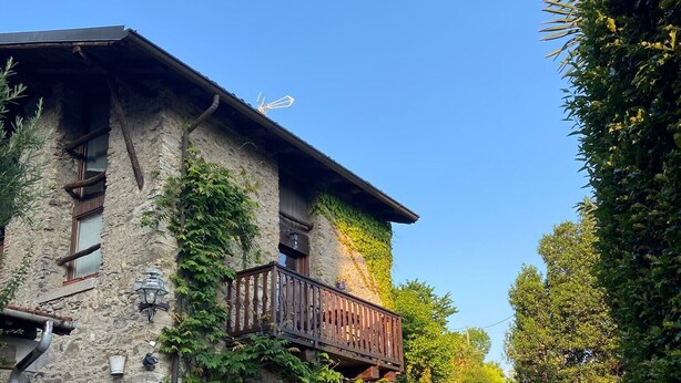 A stone building with a wooden balcony, a gravel path, and a clear blue sky. - Holiday Home 'Cascina Taronico' with Lake View and Wi-Fi (Bellagio)