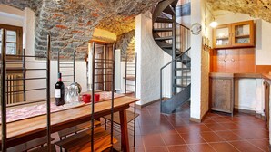 A rustic interior with a stone ceiling, a spiral staircase, a wooden dining table with chairs, and a kitchen area. - Holiday Home 'Cascina Taronico' with Lake View and Wi-Fi (Bellagio)