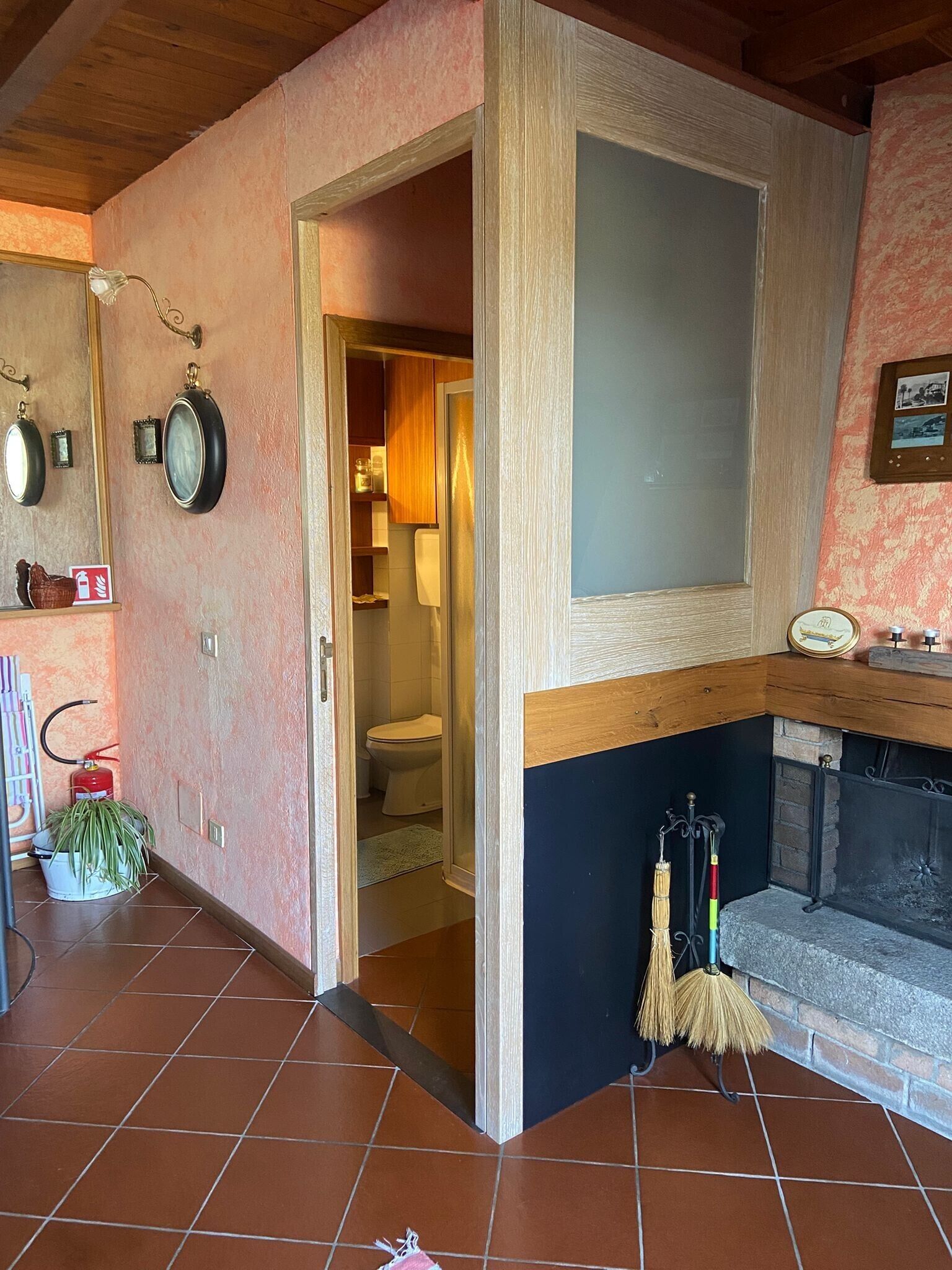 A living room with a fireplace, a door leading to a bathroom, and a tiled floor.