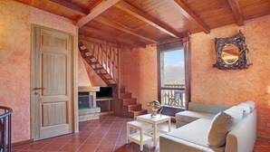 A cozy living room with a wooden staircase, a sofa, a small table, and a fireplace. - Holiday Home 'Cascina Taronico' with Lake View and Wi-Fi (Bellagio)