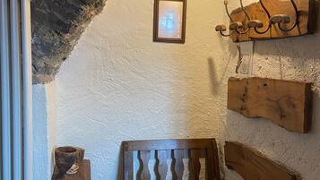 A rustic interior with a wooden bench, a wall-mounted coat rack, a framed picture, and a radiator.