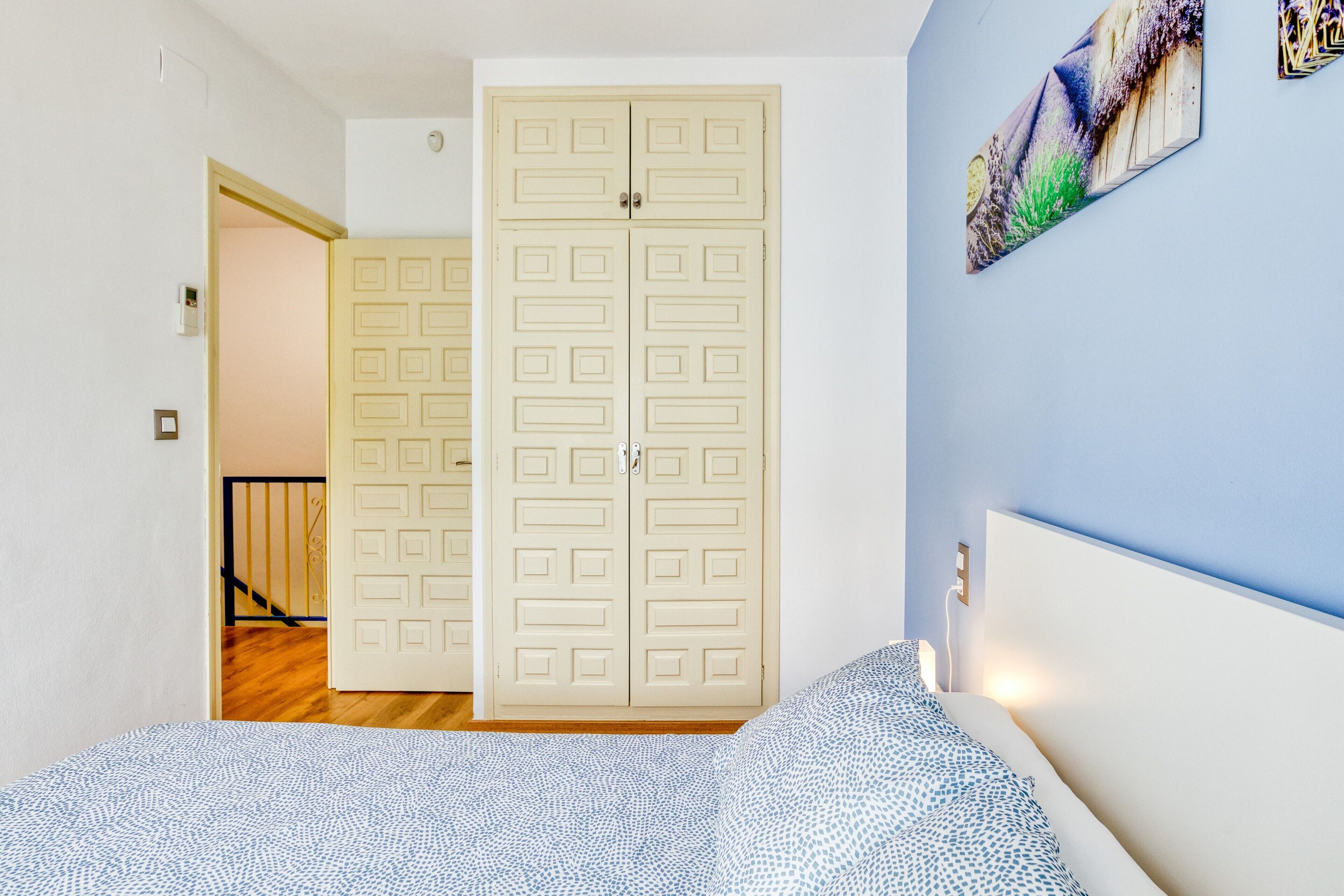 A bedroom with a bed, a wardrobe, and a painting on the wall.