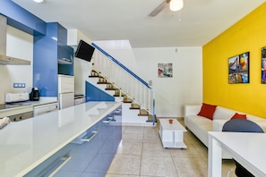 A modern kitchen with a white countertop, blue accents, a built-in oven, and a stainless steel range hood.