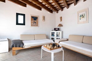 Une pièce comprenant deux canapés, une table basse en bois avec un jeu d’échecs, un meuble et une lampe.