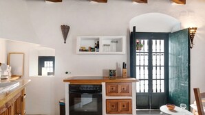 Een compacte keuken met een inbouwoven, een kleine tafel en een raam met tralies.