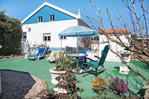 A building with a blue and white exterior, a patio with a table and chairs, and a striped umbrella.
